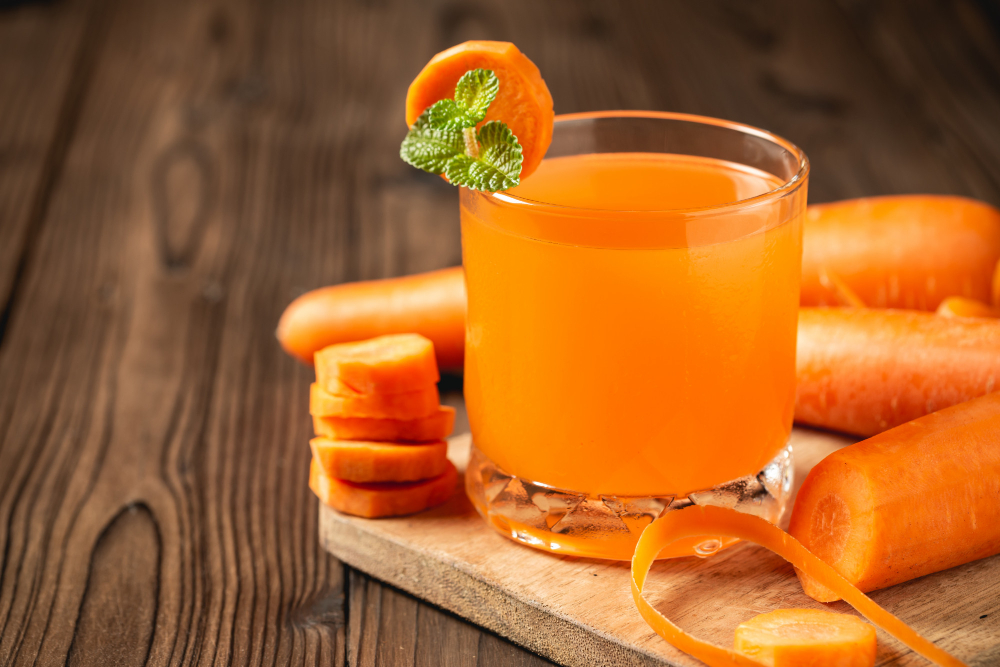 Suco Detox: Principais Benefícios Para a Saúde do Corpo 4 suco de cenoura em vidro na mesa de madeira